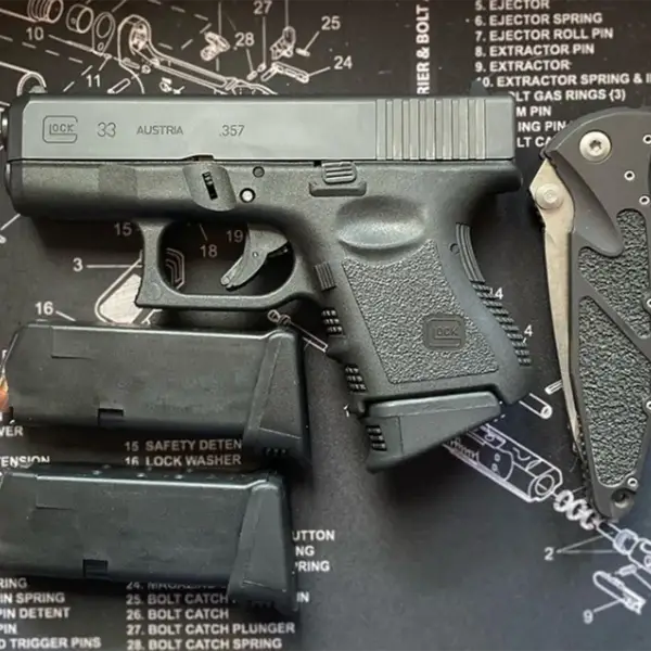 EDC flat-lay: Glock 33, spare nine-round mag, pocket light and folding knife