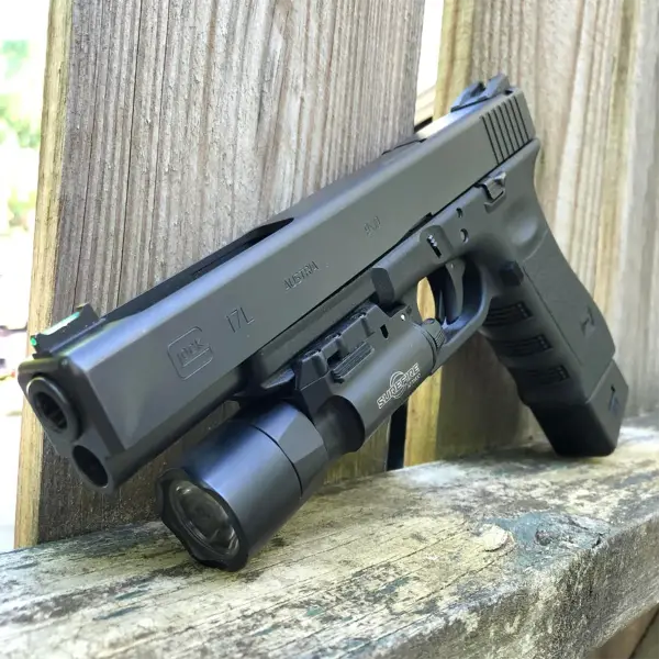 Competition flat-lay: Glock 17L with red-dot optic, magwell funnel and shot timer