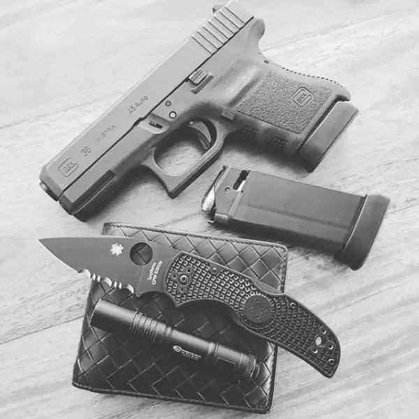 EDC flat-lay: Glock 36, spare six-round mag, pocket light and folding knife