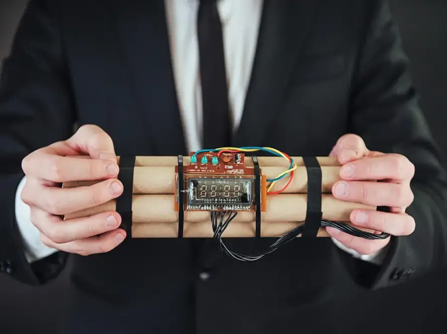 A suited expert holding a timer-equipped explosive mock-up – TNT C4 comparison and training on TNT and C4 differences.